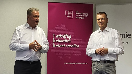 Claus Weselsky (links im Bild) Frank Schönborn (rechts im Bild) stehen in einem Raum und halten einen Vortrag.