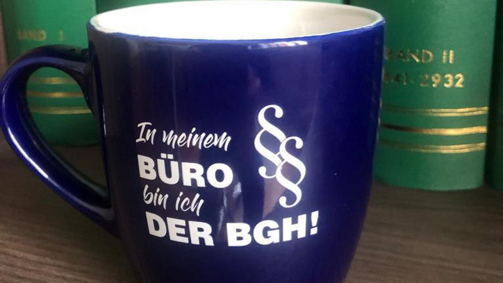 Auf dem Bild ist eine Tasse mit einem kessen Spruch: „In meinem Büro bin ich der BGH“ zu sehen.